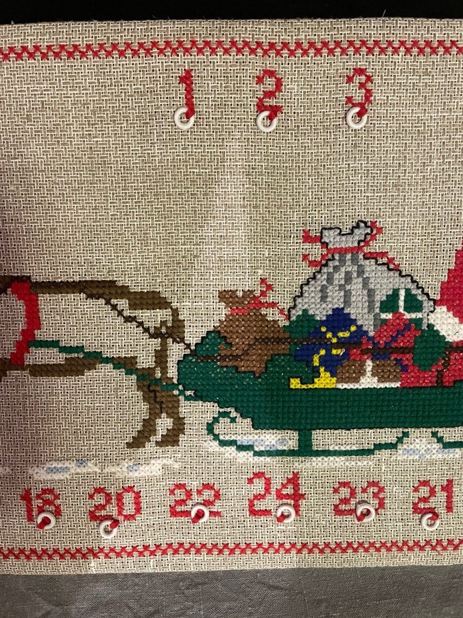 Broderad julkalender med korsstygn på tavla.